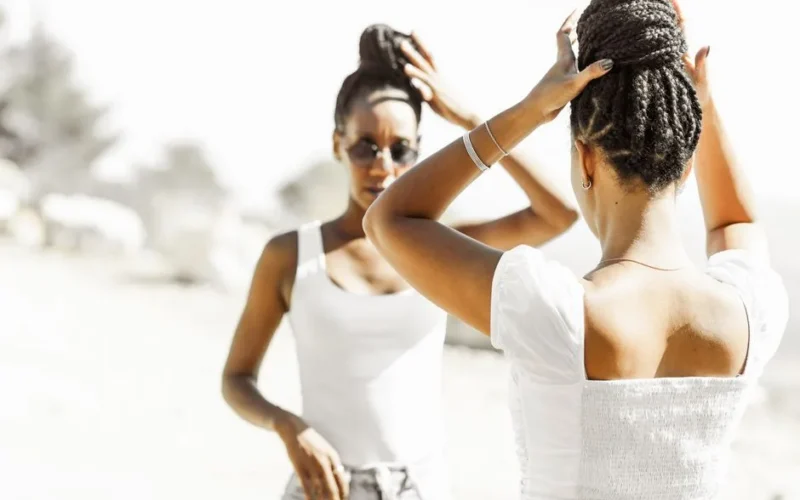 Two women styling hair in bright sunlight, creating elegant looks.