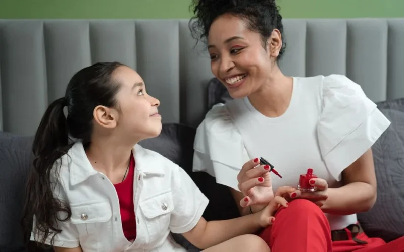 A joyful mother and daughter enjoying quality time painting nails together.