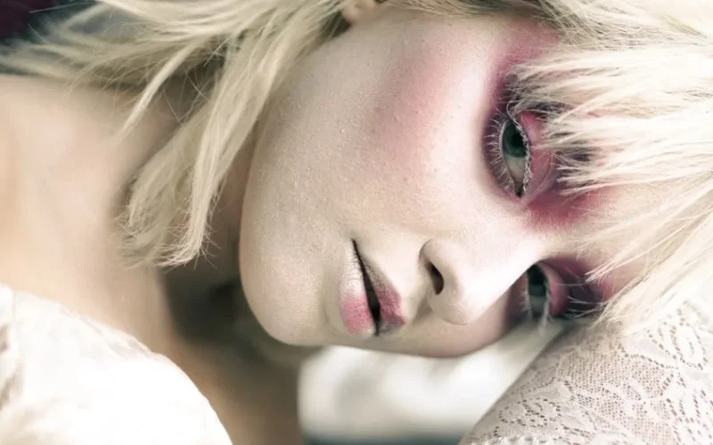 Close-up portrait of a woman with striking makeup and blonde hair, emphasizing artistic expression.