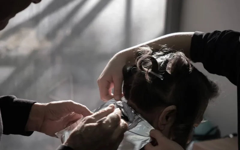 Expert hairdresser applying color highlights in a salon with natural lighting in İzmir, Türkiye.
