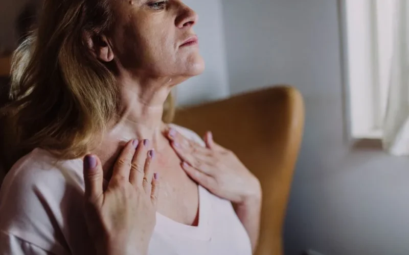A mature woman gently massaging moisturizer into her neck, highlighting skincare routine and self-care.