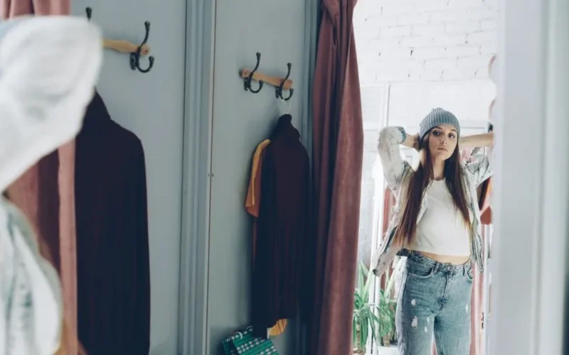 Fashionable woman in a dressing room checking her fit in the mirror.