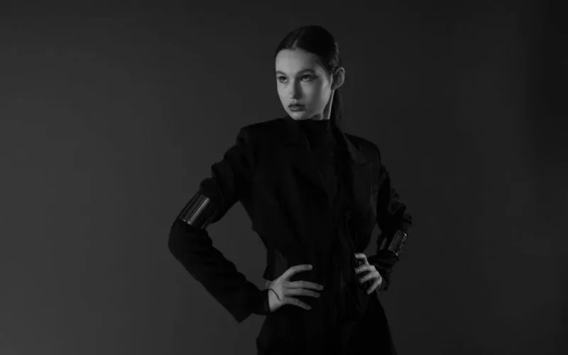 Elegant black and white studio portrait of a woman in a stylish black outfit posing confidently.