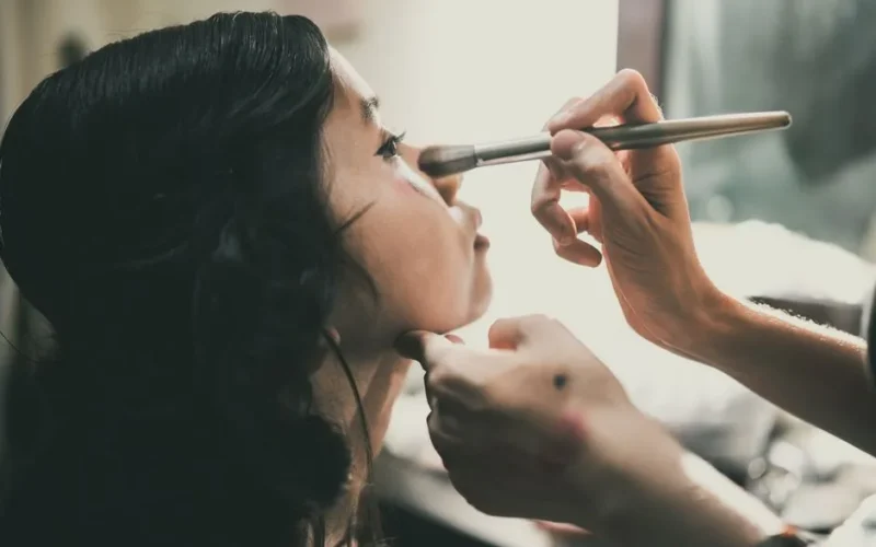 Close-up of an Asian woman getting her makeup done by a professional, emphasizing beauty and care.