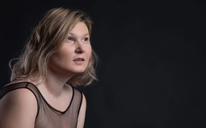 Elegant portrait of a woman with short blonde hair posing in a studio.