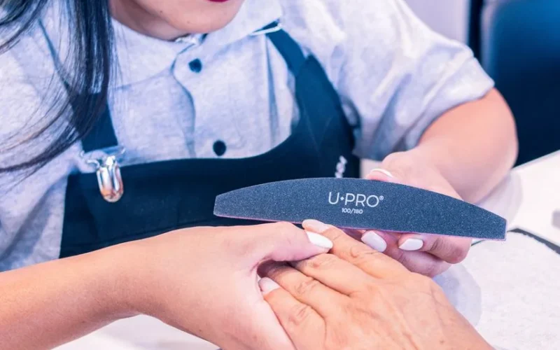 A professional nail technician provides a manicure service in a beauty salon, focusing on nail care.