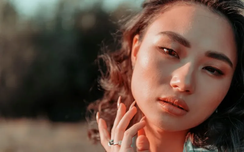 Close-up portrait of a beautiful woman with makeup outdoors, showcasing elegance and serenity.