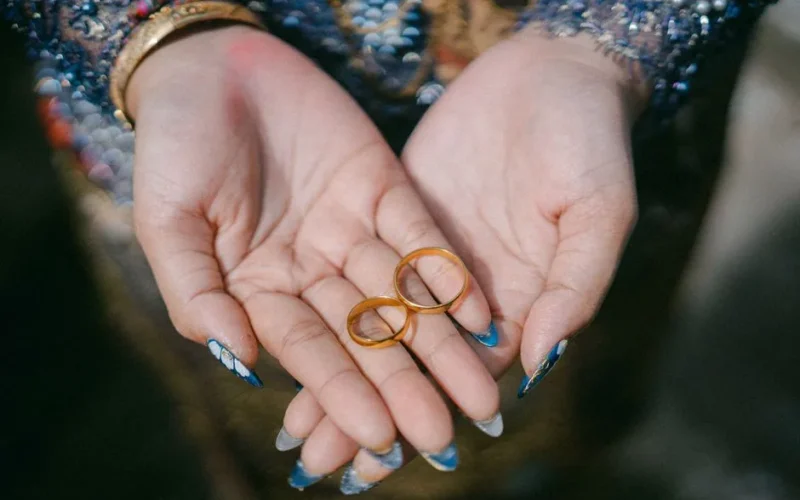 Close-up of elegant hands holding golden wedding rings, symbolizing love and commitment.