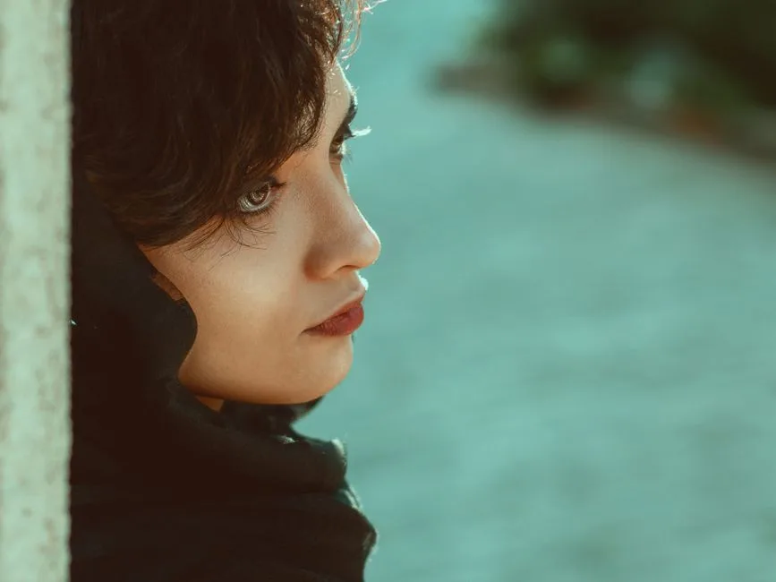 Close-up side view portrait of a thoughtful woman in soft lighting.