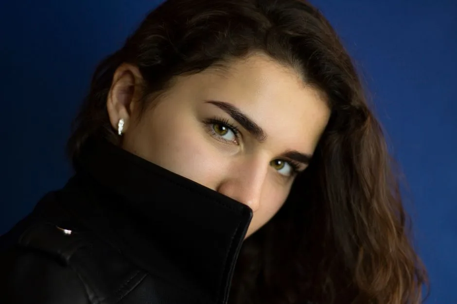 Close-up portrait of a woman with captivating eyes and a jacket collar covering her face.