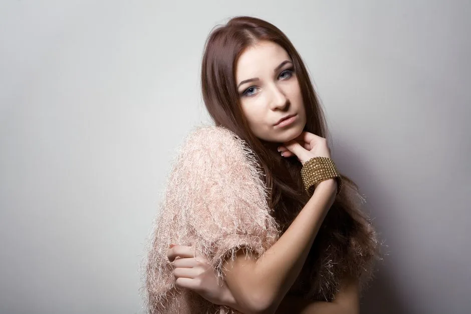 Portrait of a stylish young woman posing with a fashionable outfit, featuring a textured top and bracelet.