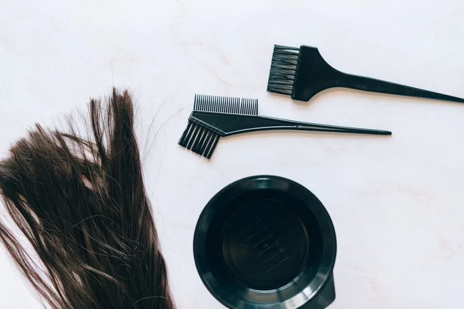 Top view of hair coloring tools and hair strands on a white background.