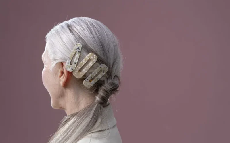Close-up portrait of a senior woman with a stylish hair barrette in a studio setting.