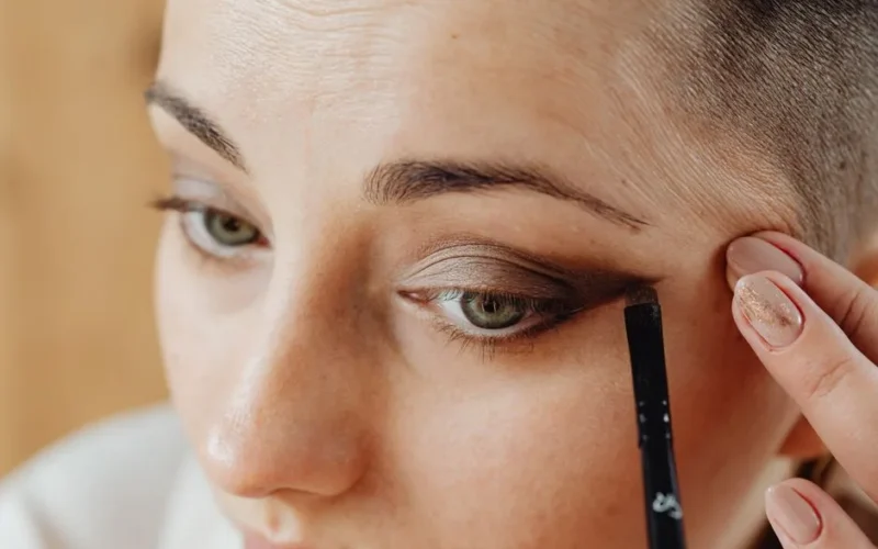 Detailed close-up of a woman applying eyeshadow with a brush.