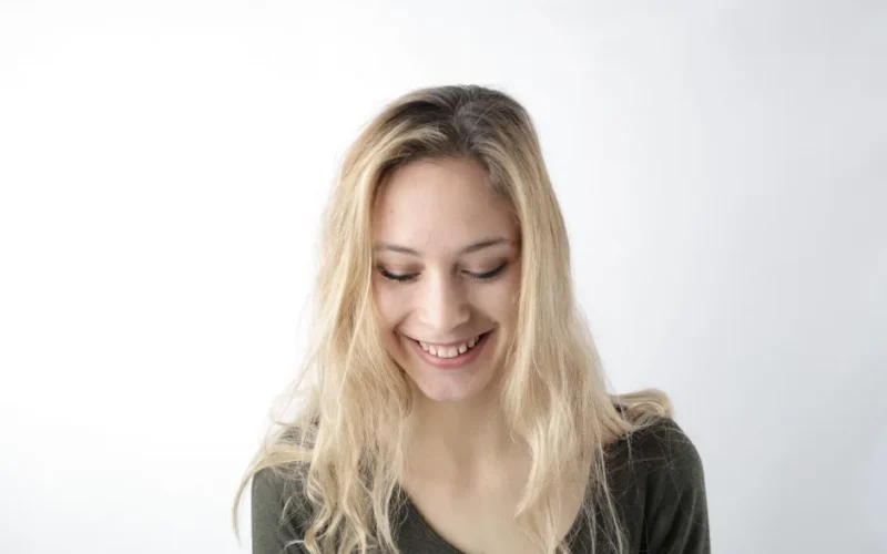 Portrait of a smiling young woman with blond hair against a white background.