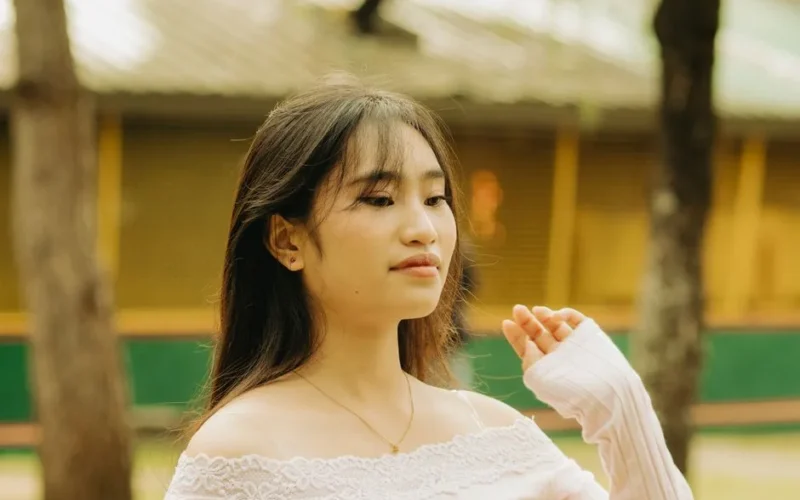 Candid portrait of a young woman with long straight hair in an outdoor park.