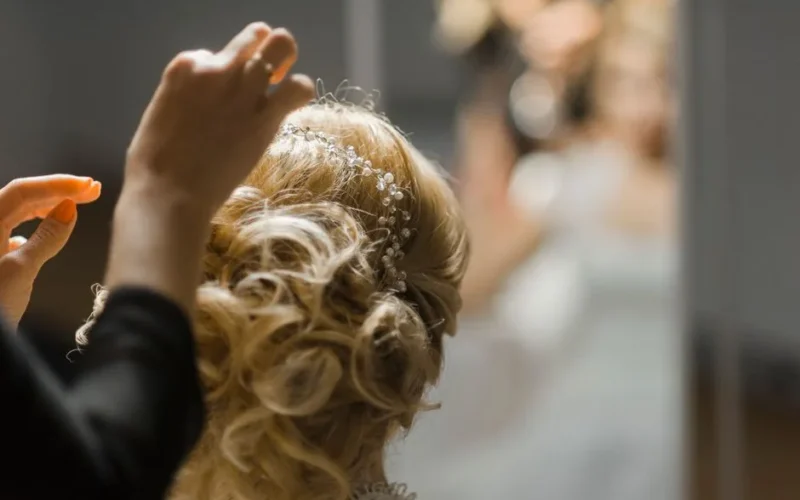 Close-up of a stylish bridal hairstyle being adjusted with intricate accessories.