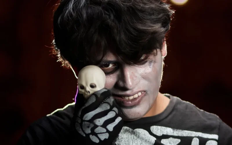 A person in skeleton makeup holding a small skull, perfect for Halloween themes.