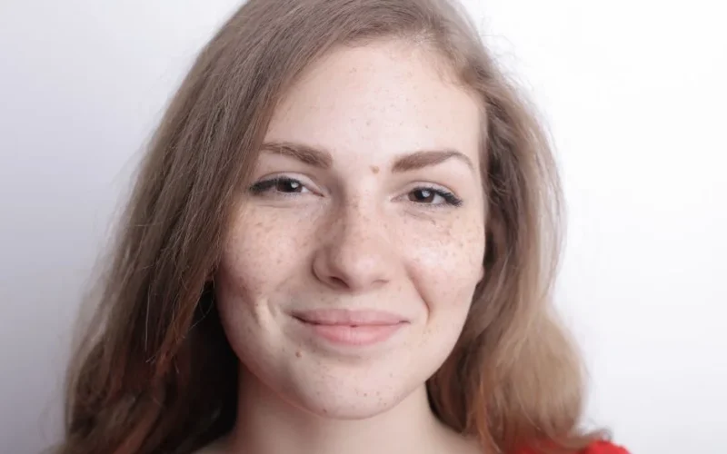 Close-up portrait of a smiling young woman with freckles and natural beauty.