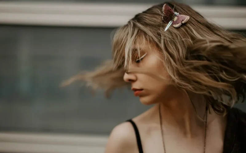 Artistic portrait of a woman with hair in motion and a butterfly clip, capturing style and motion.