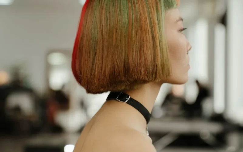 Profile shot of a woman with vibrant, multi-colored bob hairstyle in a modern studio.