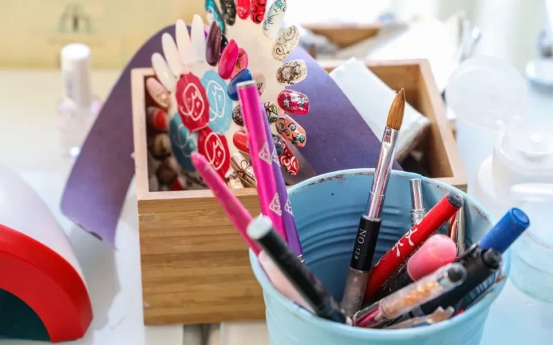 Vibrant desk scene with colorful makeup and nail art tools in containers.