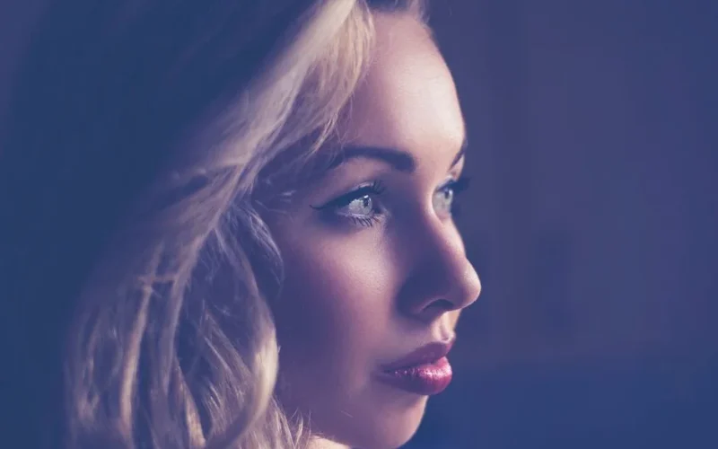 Captivating side profile of a young woman with blonde hair, expressive eyes, and soft lighting.
