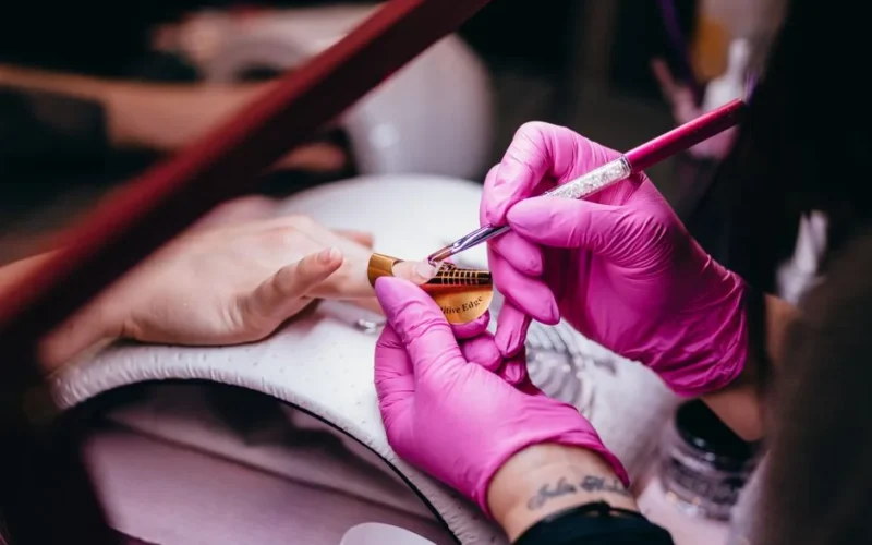 Close-up of a nail technician applying nail art in a beauty salon setting, highlighting precision and artistry.
