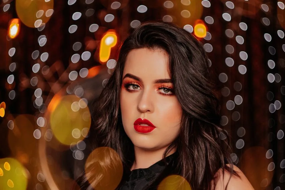 Elegant close-up of a woman with bold makeup in a bokeh lights setting.