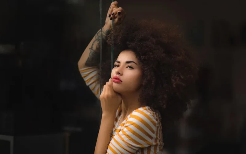 Striking portrait of a woman with an afro hairstyle, wearing a striped shirt and contemplating.