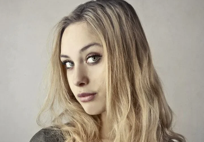 Close-up portrait of a young woman with blonde hair and captivating eyes.