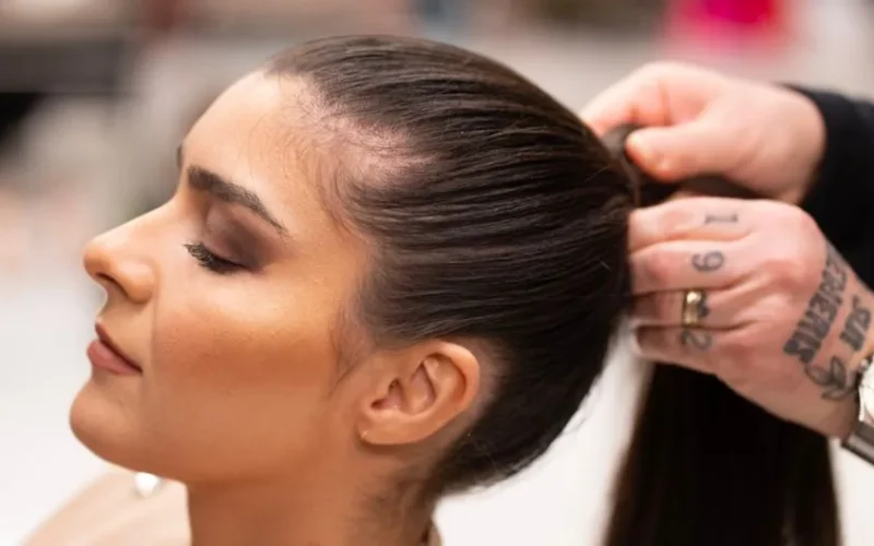Close-up of a hairstylist tying a woman's hair in a sleek ponytail in Milan, Italy.