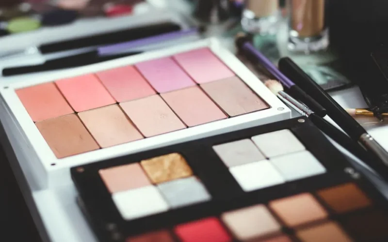 Close-up of colorful makeup palettes with brushes, perfect for beauty and fashion themes.