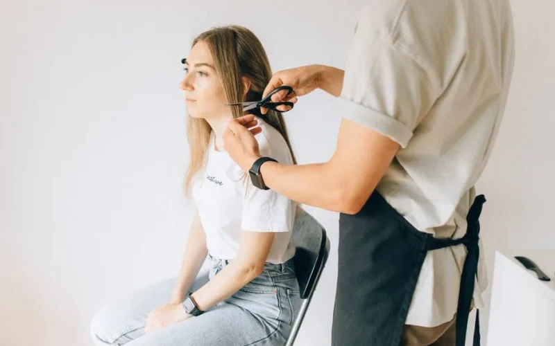 A woman gets her hair professionally cut by a hairstylist in a modern salon.